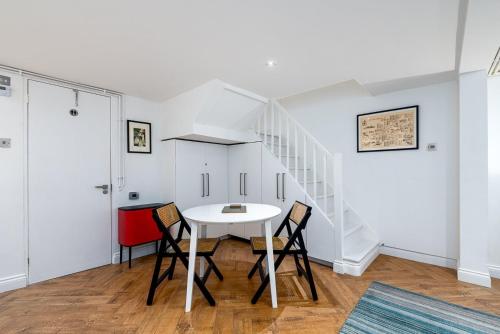 伦敦GuestReady - Charming studio in Hackney的一间配备有白色桌椅的用餐室