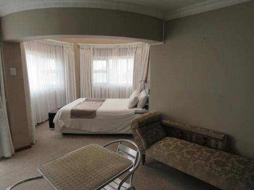 圣赫勒拿湾St Helena Bay Hotel的一间卧室配有一张床、一把椅子和一张沙发