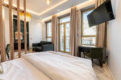 海若克利欧Royal Gold City Suites by Estia的一间卧室配有一张床、一张书桌和一台电视