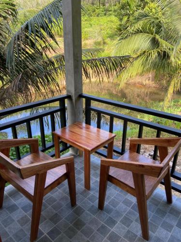 瑶亚岛Green Mountain Resort Koh Yao的阳台设有3张木制长椅和1张桌子
