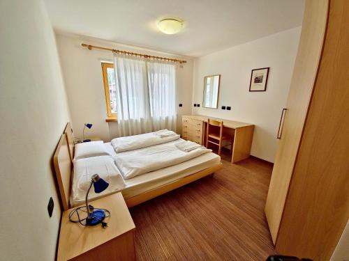 卡纳泽伊Alpe Di Gries Sella Ronda Dolomiti的一间卧室配有一张床、一张书桌和一个窗户。