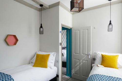 巴斯巴斯堡街梦幻旅馆 的配有两张带黄色枕头的床的带门的房间
