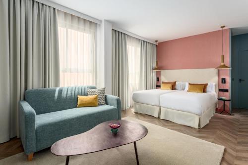 马德里法庭公寓式酒店的酒店客房配有床、沙发和椅子