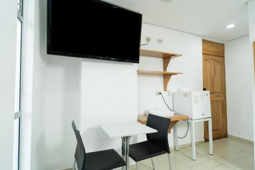伊塔圭Hotel Portal Central的客厅配有书桌和墙上的电视