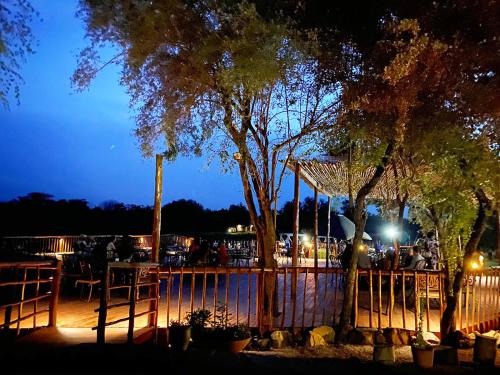 哈博罗内Crocodile Pools Resort的庭院在晚上设有栅栏和树木