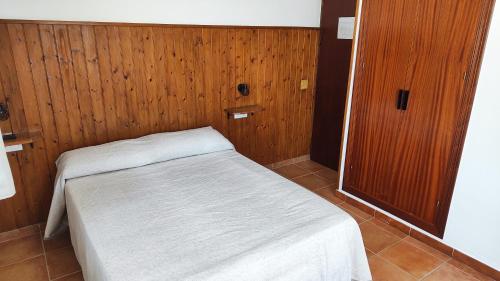 萨阿拉德洛斯阿图内斯Hostal Jadraza的木墙客房内的小床