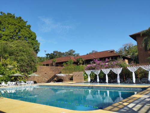 伊瓜苏港若爱查斯日欧诺酒店的一座带椅子和遮阳伞的游泳池位于一座建筑旁边