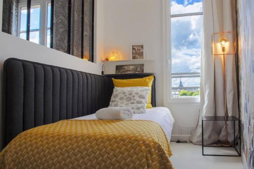 凡尔赛SweetHomeVersailles 5mn walk from the Palace的一间卧室配有一张带黄色毯子和窗户的床