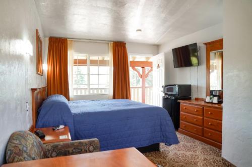 沙斯塔山瑞士假日汽车旅馆的一间卧室配有蓝色的床和电视