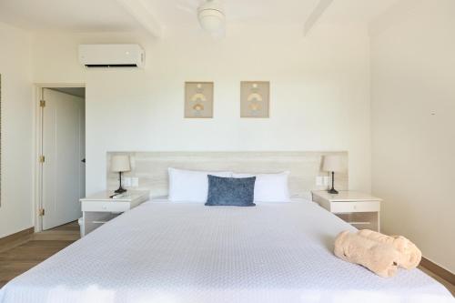 塔马林多Hotel Perla de la Playa的白色卧室配有白色大床和蓝色枕头