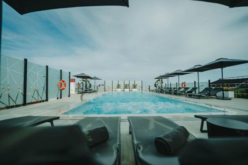 马拉加Hotel Málaga Nostrum Airport的一个带桌椅的大型游泳池