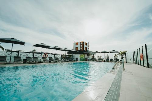 马拉加Hotel Málaga Nostrum Airport的一个带椅子和遮阳伞的大型游泳池
