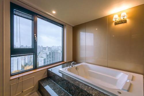 首尔JK盛开酒店的一间带大浴缸和大窗户的浴室