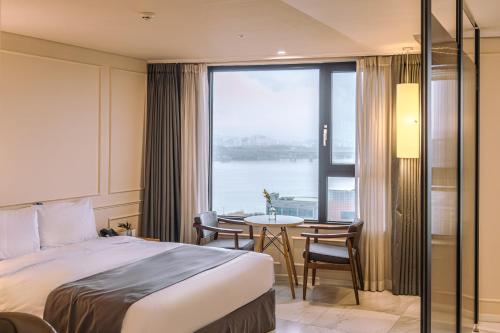 首尔JK盛开酒店的酒店客房设有床、桌子和窗户。