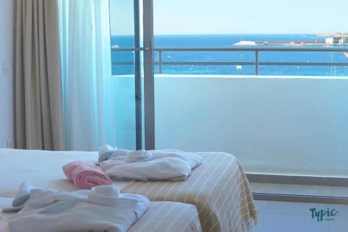 圣安东尼奥湾Typic Marina Playa - Adults Only的一间卧室配有带毛巾的床和窗户。