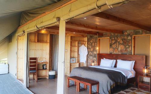 OlolaimutiekAlama Camp Mara的木制客房内的一间卧室,配有一张床