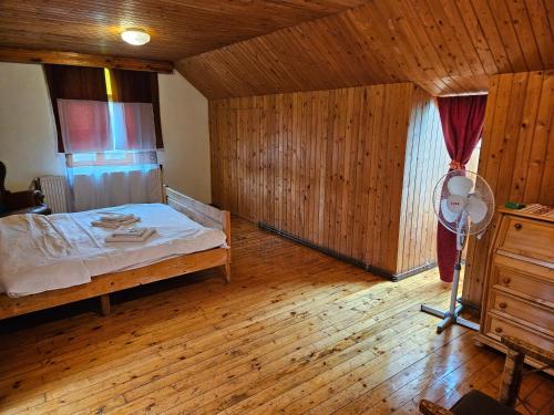 拉姆尼库沃尔恰Casa de pe lac Fedelesoiu ,的一间卧室配有一张床,铺有木地板