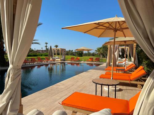马拉喀什Pavillon du Golf -Palmeraie suites的游泳池旁的游泳池配有橙色椅子和遮阳伞