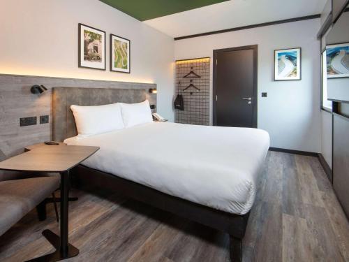 克劳利ibis Styles London Gatwick Airport的酒店客房设有一张大床和一张桌子。