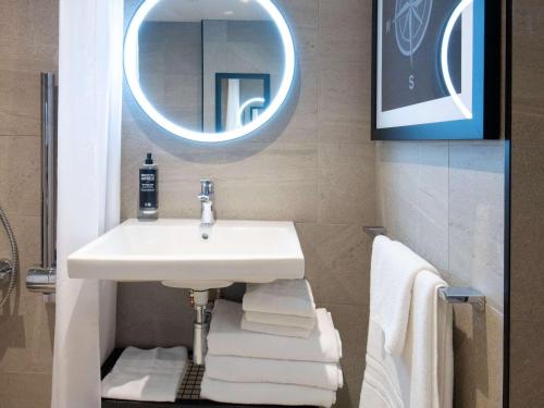 克劳利ibis Styles London Gatwick Airport的浴室配有盥洗盆、镜子和毛巾