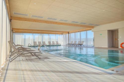 维塞乌卡Hotel GLAR Conference & SPA的大楼内带椅子的大型游泳池