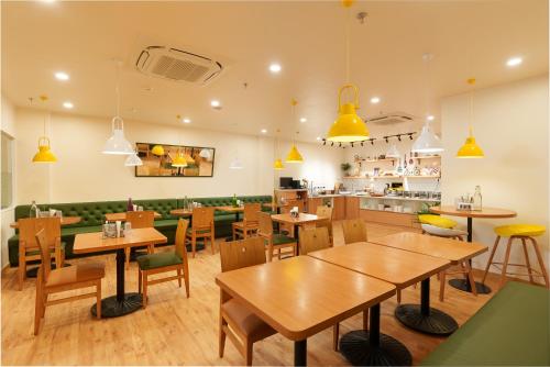 新德里Bloom Hotel - GK2的餐厅设有木桌和绿色椅子