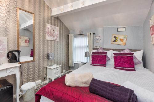 布莱克浦Friends Hotel的一间卧室配有一张带红色枕头的大床