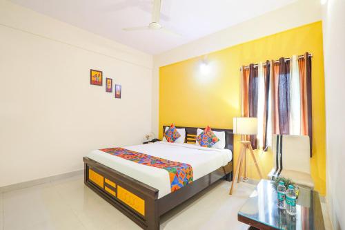 海得拉巴FabHotel Namaha Suites的一间卧室设有一张床和黄色的墙壁