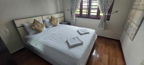 Thôn Trường GiangMelody Riverside Homestay的卧室配有带枕头的白色床和窗户。