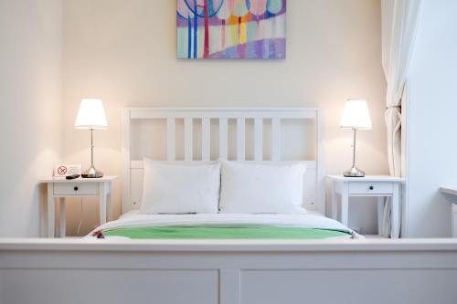 利沃夫达尼罗宾馆的一间白色卧室,配有一张床和两盏灯