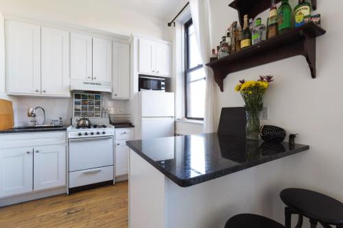 纽约Sunny Stylish West Village Condo的厨房配有白色橱柜和黑色台面