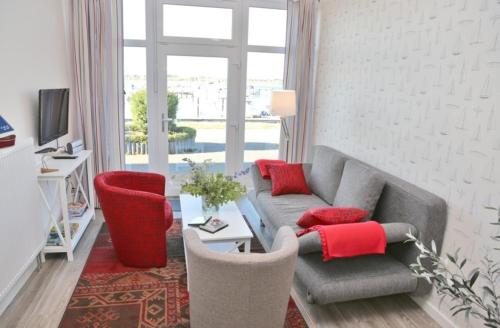 费曼城堡Am Rundsteg 4的客厅配有灰色沙发和红色枕头