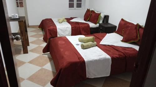 通哈Hotel Colonial El Bosque的一间设有三张红色和白色床单的房间