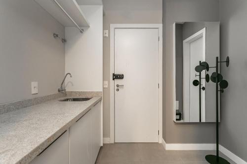 弗洛里亚诺波利斯Studios novos em condomínio com foodhall #TopTower的白色的厨房配有水槽和镜子