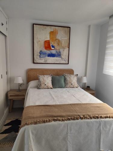 塞维利亚Agradable Dúplex Terraza Virgen del Rocio的卧室配有一张床,墙上挂有绘画作品