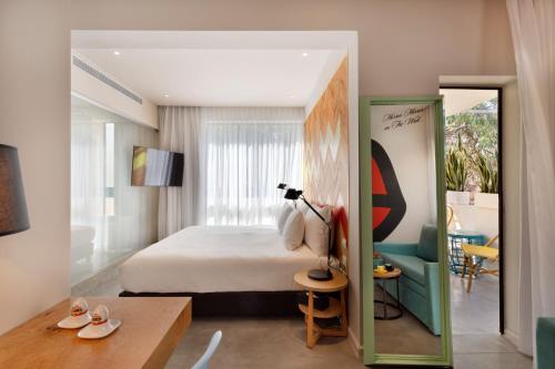 特拉维夫Cucu Hotel By 7Minds的卧室配有1张床、1张桌子和1把椅子