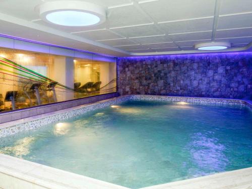 达曼达曼商业园诺富特酒店的紫色照明室里的一个大型游泳池