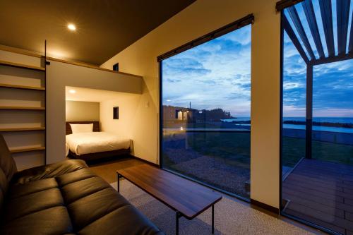 坂井市Oruga Resort -Trailer Cottage & Cafe -的客房设有沙发、床和大窗户。