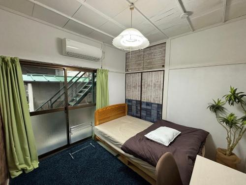 汤河原町温泉街の入り口にあるゲストハウス SLOW HOUSE yugawara的一间小卧室,配有床和窗户