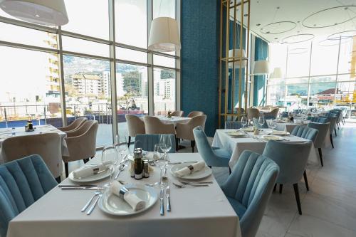 布德瓦Apartments Lux sea view的餐厅设有白色的桌椅和窗户。