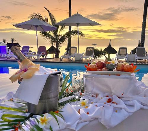 蒙舒瓦西Coral Azur Beach Resort Mont Choisy的一张桌子,桌子上摆着食物和饮料,在游泳池边
