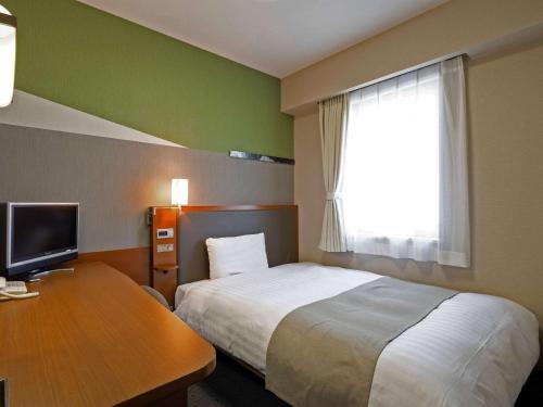 富山舒适酒店富山的配有一张床、一张书桌和一扇窗户的酒店客房