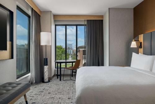 路易斯威尔Tempo By Hilton Louisville Downtown Nulu的酒店客房设有一张床、一张书桌和窗户。