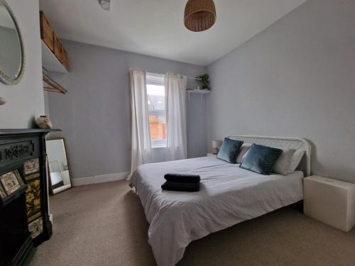 惠特利湾Lovely 3 bedroom Whitley Bay Townhouse.的一间卧室配有一张带蓝色枕头的床和一扇窗户。