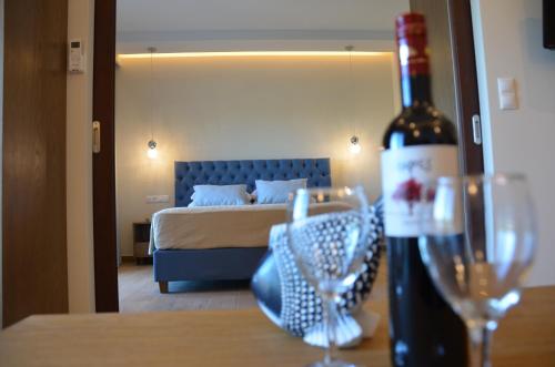 帕莱欧卡斯提撒奥德修斯酒店的一间卧室配有一张床,桌子上备有一瓶葡萄酒