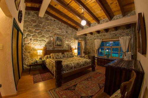 ZitácuaroHotel Rancho San Cayetano的一间卧室设有一张床和石墙