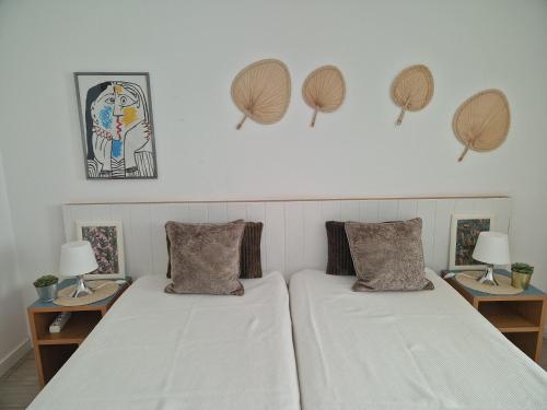 蒙蒂戈杜Apartamentos Dom Henrique的一间卧室设有两张床和两张带台灯的桌子。