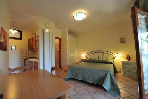 Montefiore dellʼAso帕特里齐亚度假屋的一间卧室配有一张床铺和一张桌子,还设有一间厨房