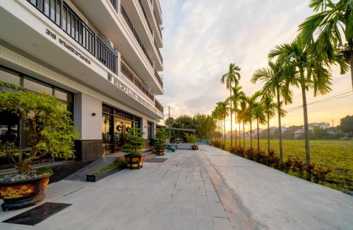 会安Eco Lux Riverside Hotel & Spa的棕榈树建筑外的走道