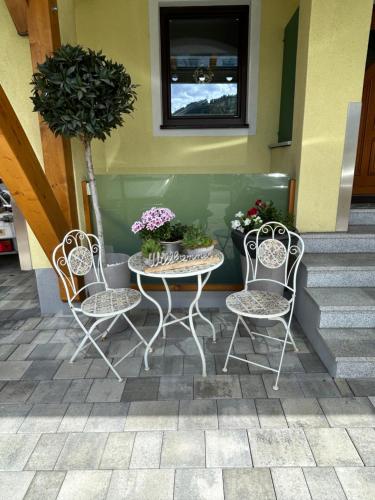 卡普伦Haus Laubreuter的庭院里设有两把椅子和一张带鲜花的桌子